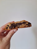 Cookie Pain Plaisir cu ciocolată Michel Cluizel 72% și alune, ținut în mână după prima mușcătură